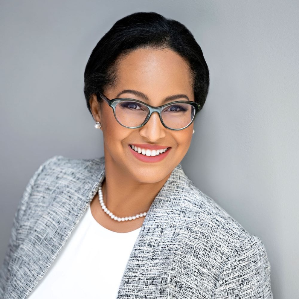 Headshot of woman with short dark hair wearing glasses with a large smile.