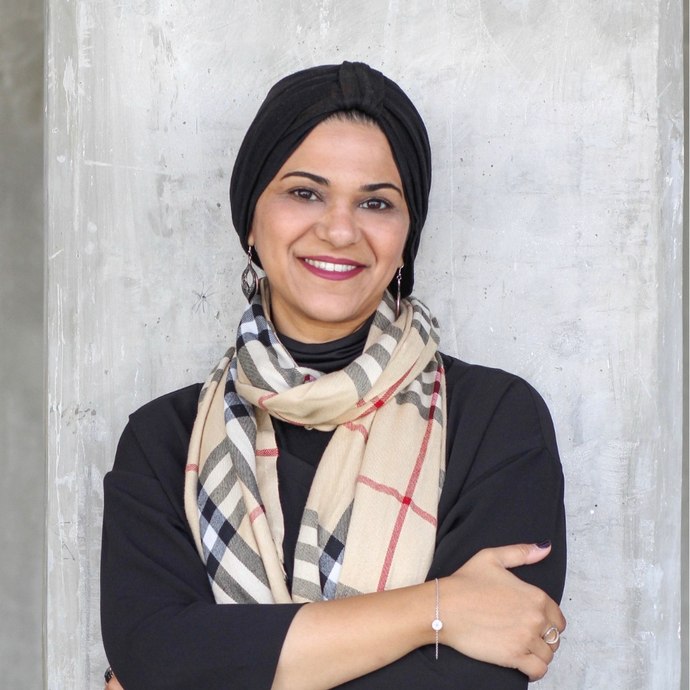 Headshot of woman with plaid scarf and black hijab.