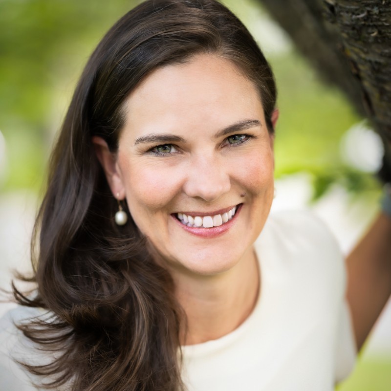 Headshot of woman with short dark hair wearing glasses with a large smile.